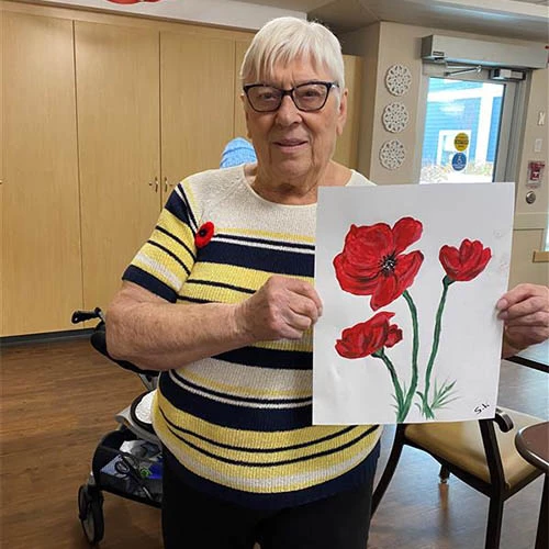 A woman holding a painting of poppies.