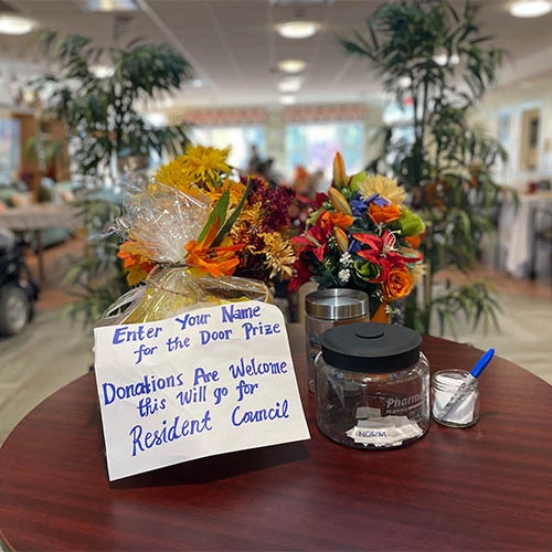 Display for a door prize draw. Flowers are placed behind the sign and jar to enter the draw.