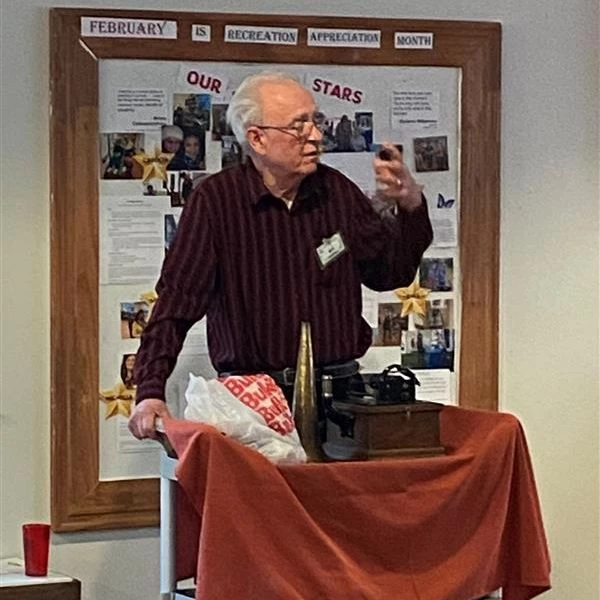 Man standing and displaying devices on a table.