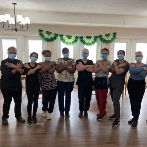 Staff members posing together for a photo with arms crossed in an embracing gesture