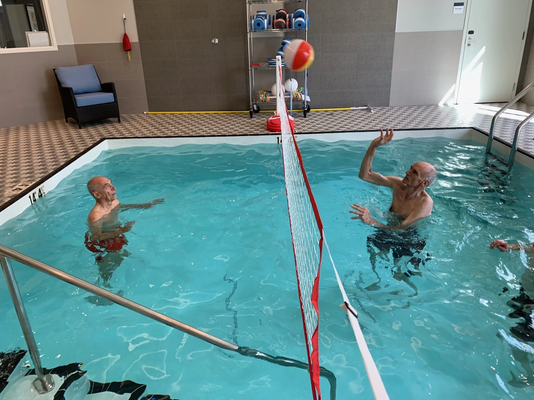 Senior citizens playing volleyball in pool