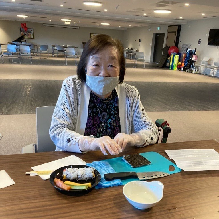 An elderly lady making sushi
