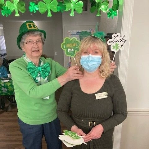 Senior dressed as a leprechaun posing with a staff member.