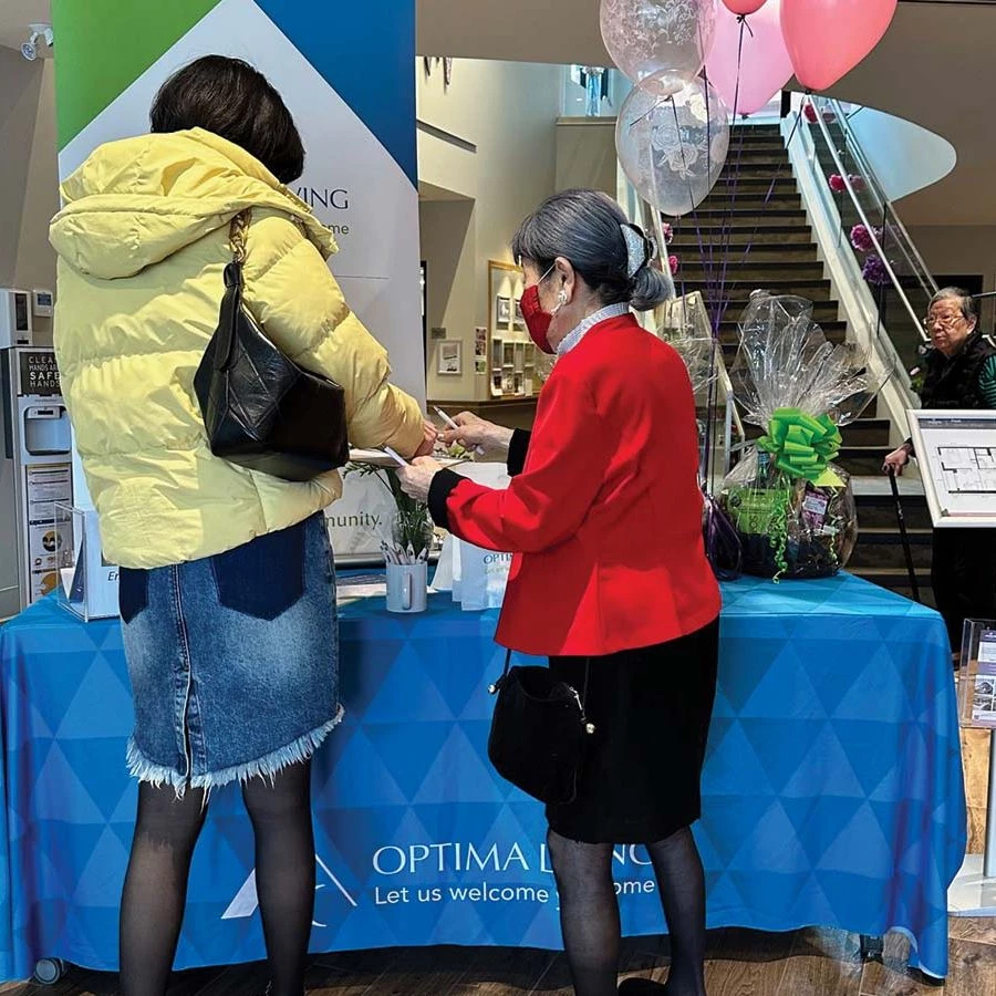 Two women standing at the Optima Living table in Wisteria Place