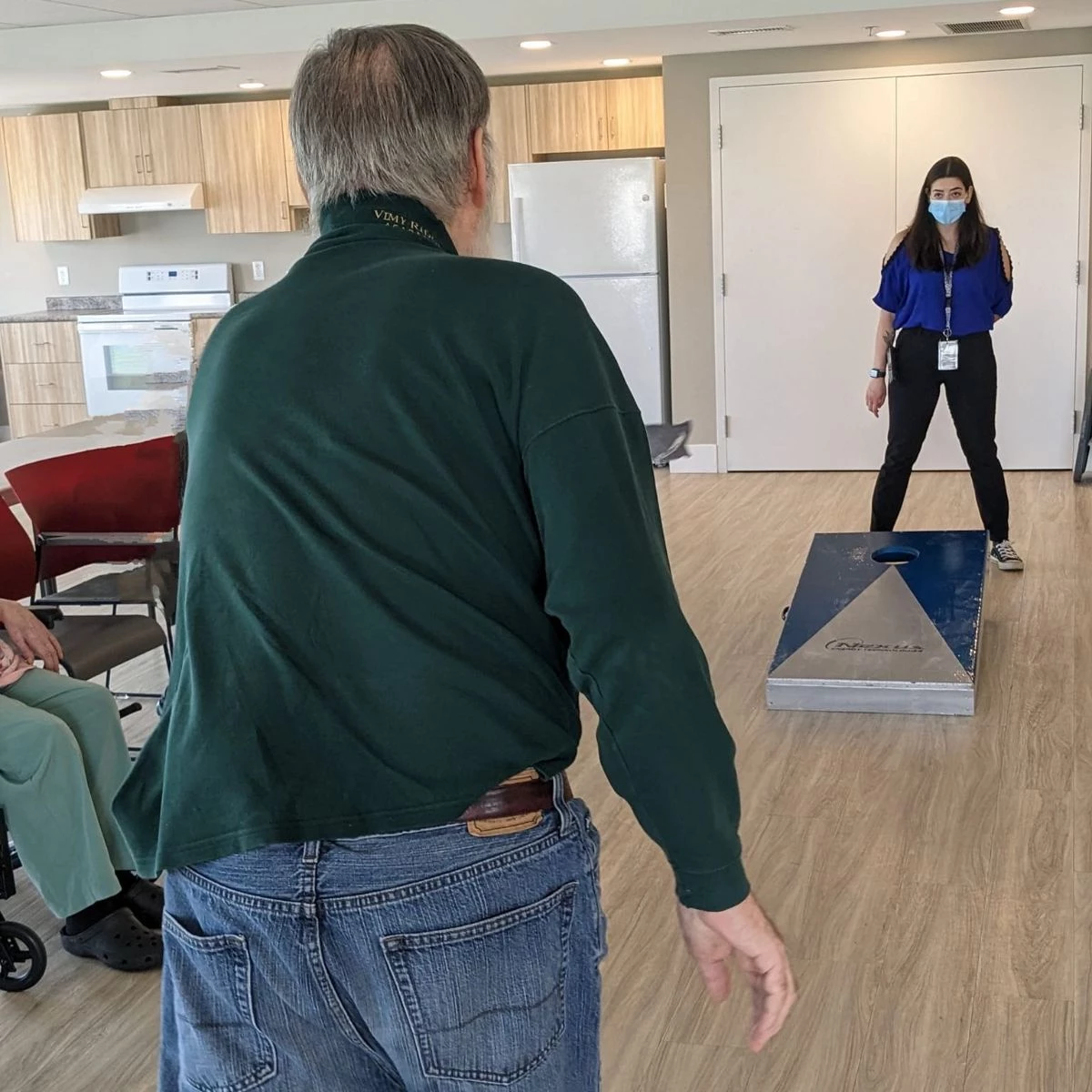 An action shot of a senior playing a staff member in a game of corn-hole.